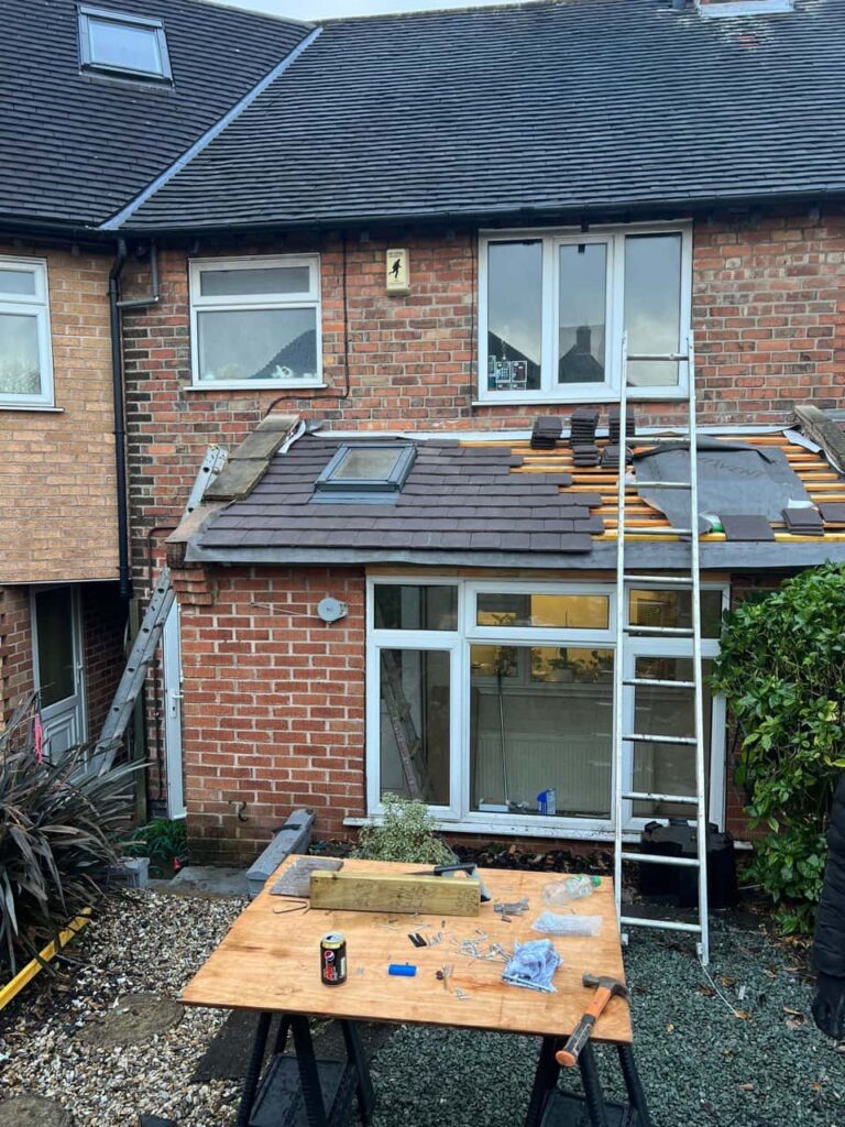 This is a photo of a roof extension that is having new roof tiles installed. This is a photo taken from the roof ridge looking down a tiled pitched roof on to a flat roof. Works carried out by Heanor Roofing Repairs